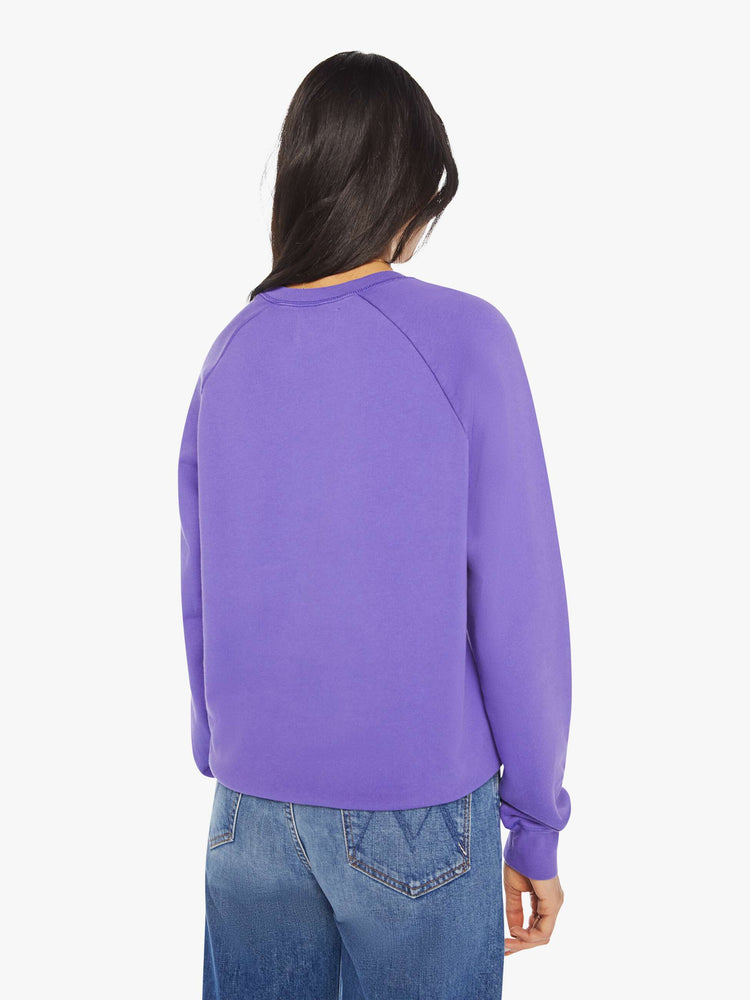Back view of a woman view of a woman crewneck sweatshirt in a purple hue with a white anchor and has a relaxed shape with raglan sleeves.