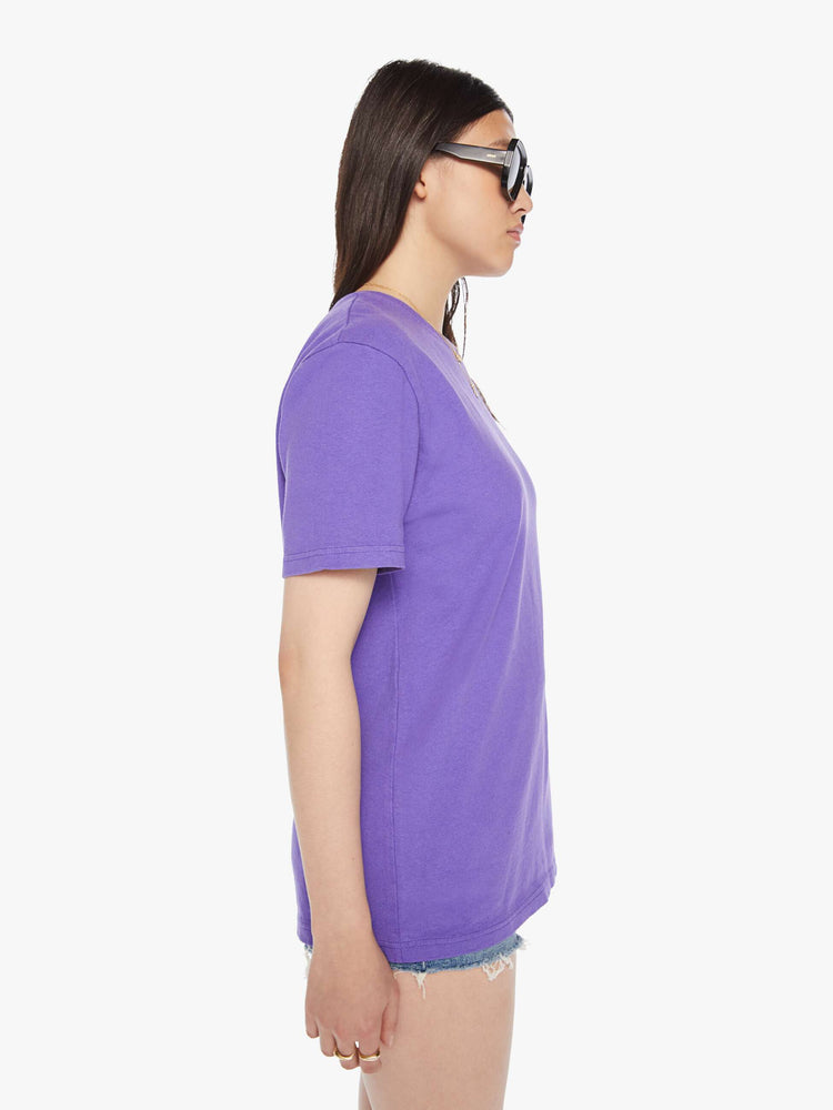Side view of a woman purple tee with a white anchor on the chest, has a ribbed crewneck and a straight fit.