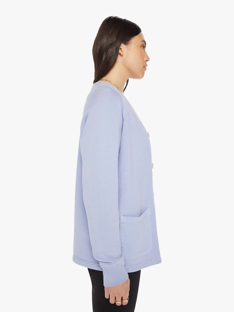 Side view of a woman light blue button-up cardigan with a V-neck, front patch pockets and a slightly boxy fit.