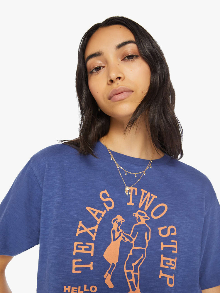 Close up view of a woman classic crewneck with a slightly boxy shape, in navy blue, the tee features an orange Texas Two Step graphic.