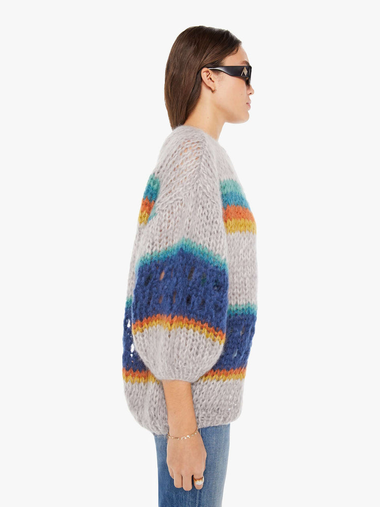 Side view of a womens chunky knit cardigan in multi color stripes, featuring a cropped body with balloon sleeves.