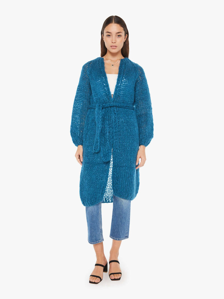 Front view of a womens loose knit blue cardigan coat featuring billow sleeves and a knit belt tie.