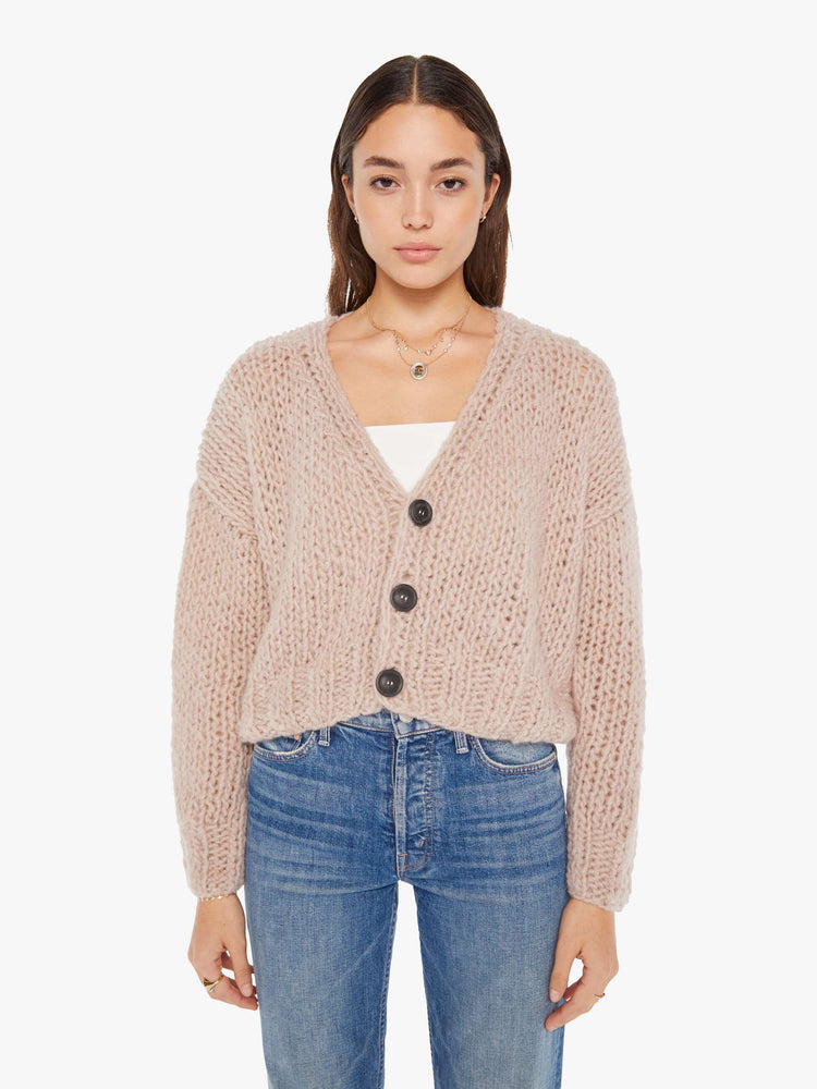Front view of a womens chunky knit cardigan in a neutral pink hue, featuring a cropped body and three large buttons.