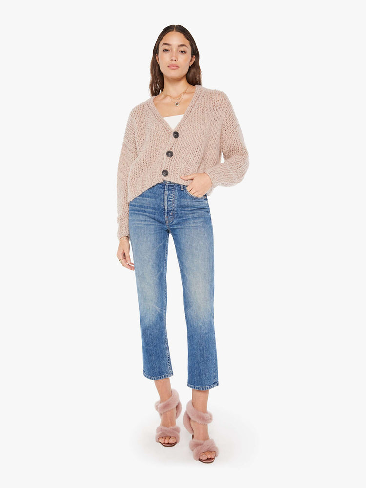 Front full body view of a womens chunky knit cardigan in a neutral pink hue, featuring a cropped body and three large buttons.