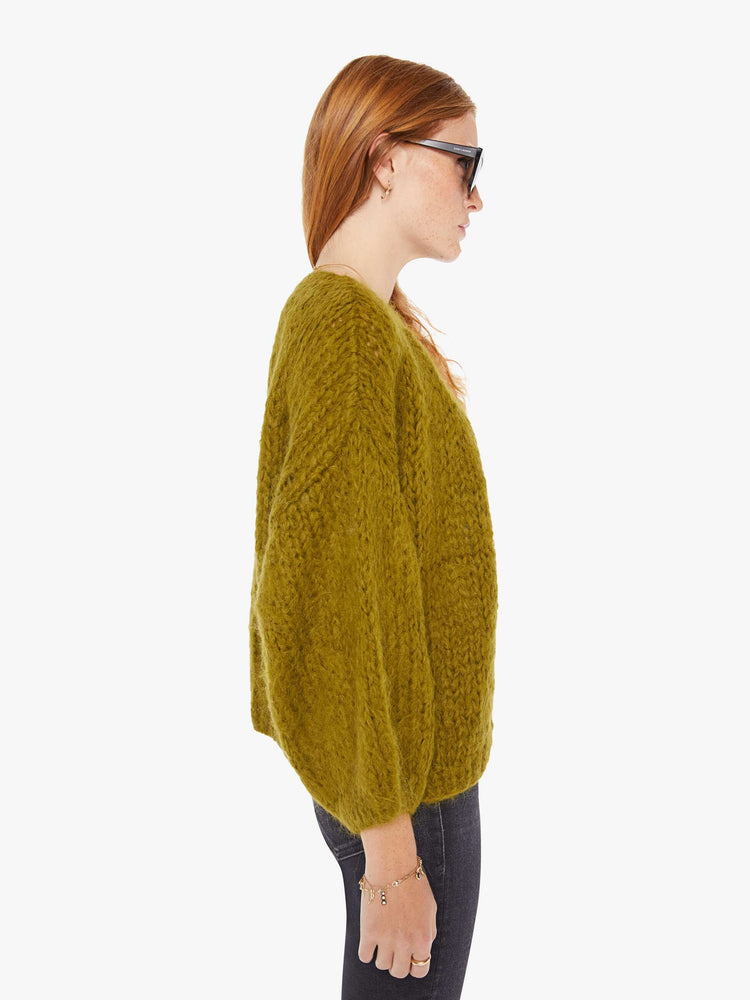 Side view of a womens chunky knit cardigan in a khaki hue featuring billow sleeves.