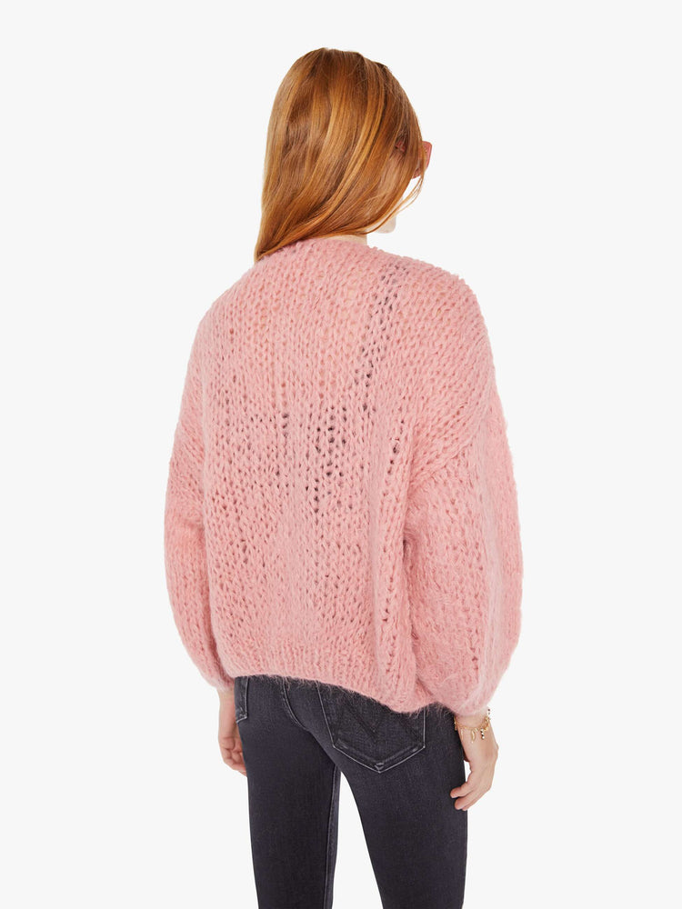 Back view of a womens chunky knit cardigan in a soft pink hue featuring cropped billow sleeves.