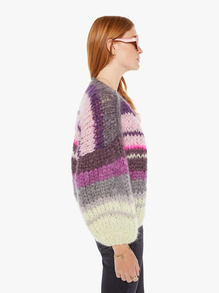 Side view of a womens chunky knit cardigan in multi color stripes, featuring a cropped body with balloon sleeves.