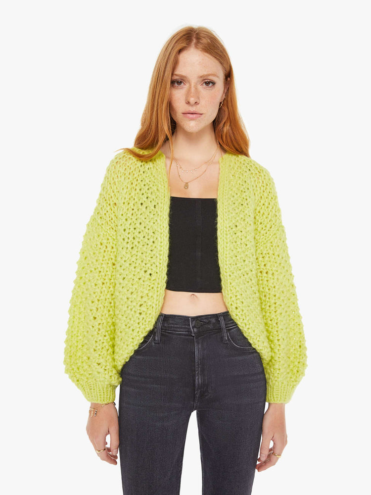 Front view of a womens chunky knit cardigan in a neon yellow hue featuring cropped billow sleeves.
