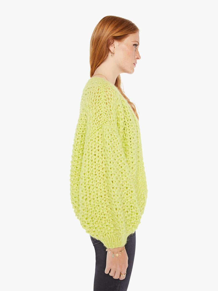 Side view of a womens chunky knit cardigan in a neon yellow hue featuring cropped billow sleeves.