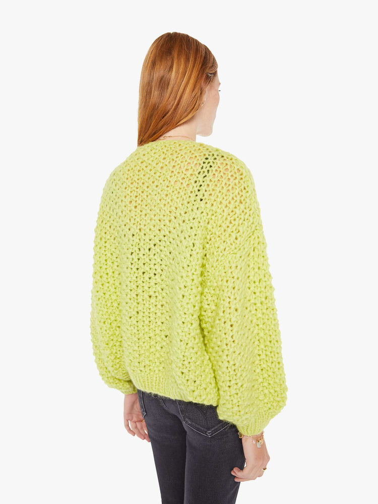 Back view of a womens chunky knit cardigan in a neon yellow hue featuring cropped billow sleeves.