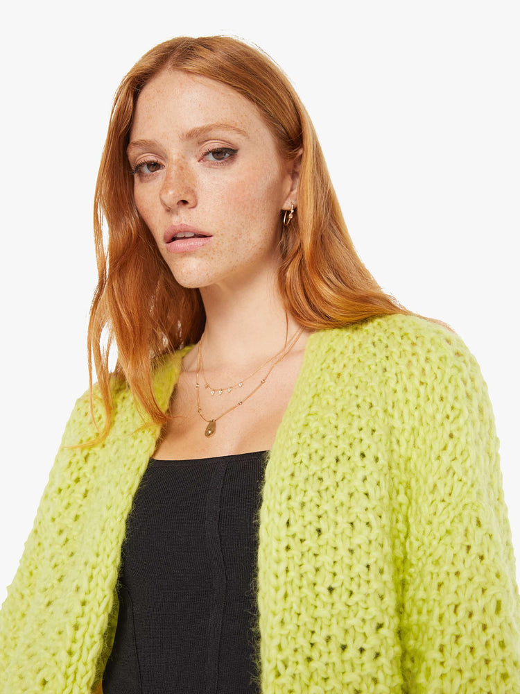 Front close up view of a womens chunky knit cardigan in a neon yellow hue featuring cropped billow sleeves.