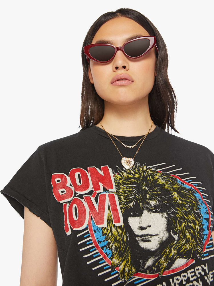 Close up view of a woman distressed crewneck tee in black, the tee pays homage Bon Jovi with bold text and graphic portrait on the front.