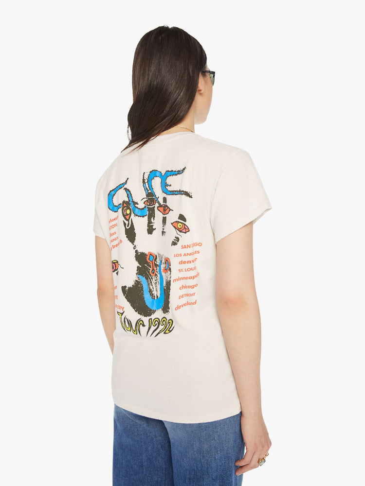 Side view of a woman distressed crewneck tee in white, the tee riffs The Cure's tour merch from 1992 with trippy graphics and bold text on the front and back.
