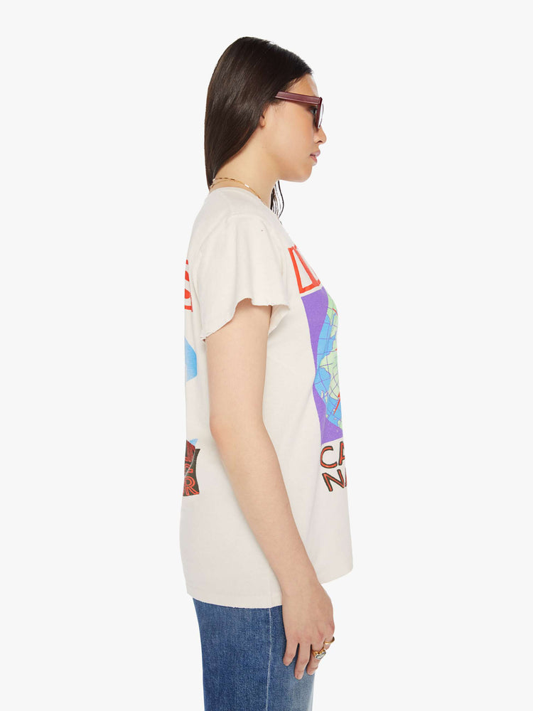 Side view of a woman distressed crewneck tee in white, the tee pays homage to INXS' Calling All Nations tour with bold graphics on the front and back.