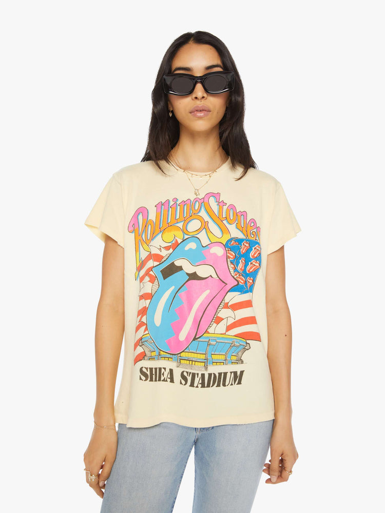 Front view of a woman hand distressed crewneck tee in a pastel yellow hue the tee riffs on the Rolling Stones' Steel Wheels tour with the band's iconic tongue-and-lips logo on the front and tour dates on the back.