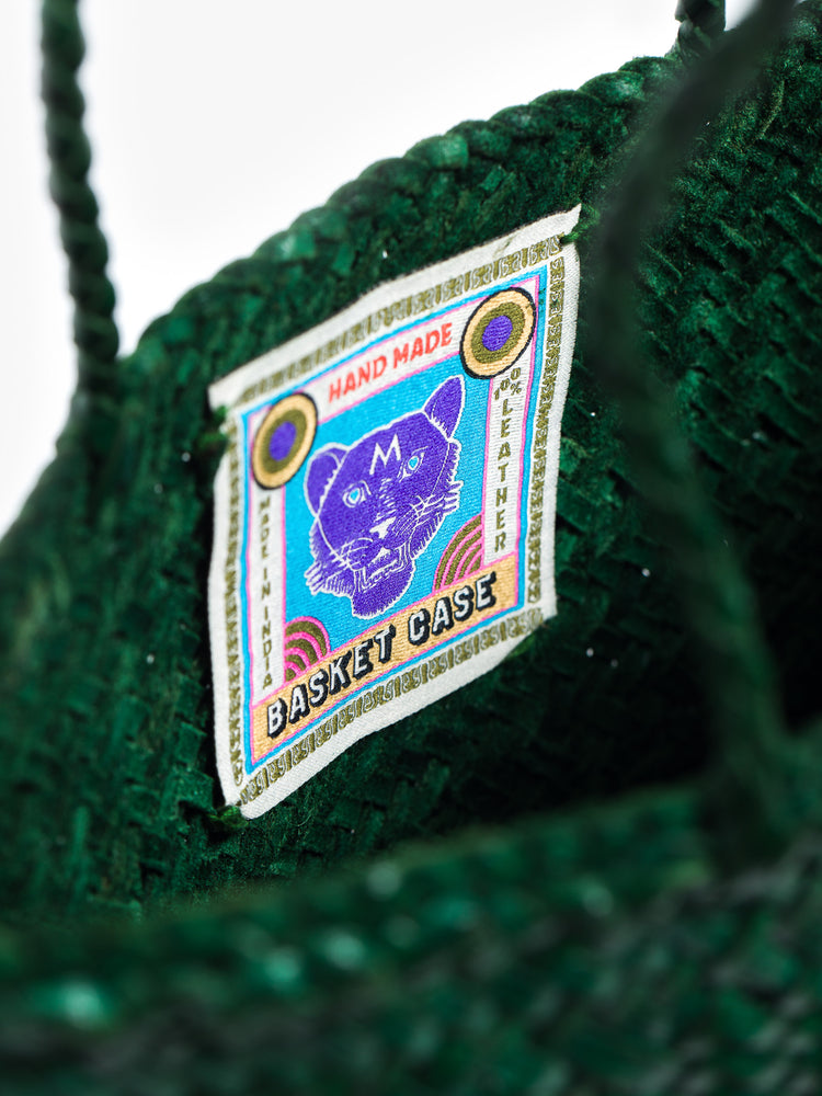 Close up view of a label inside a dark green leather woven bag.