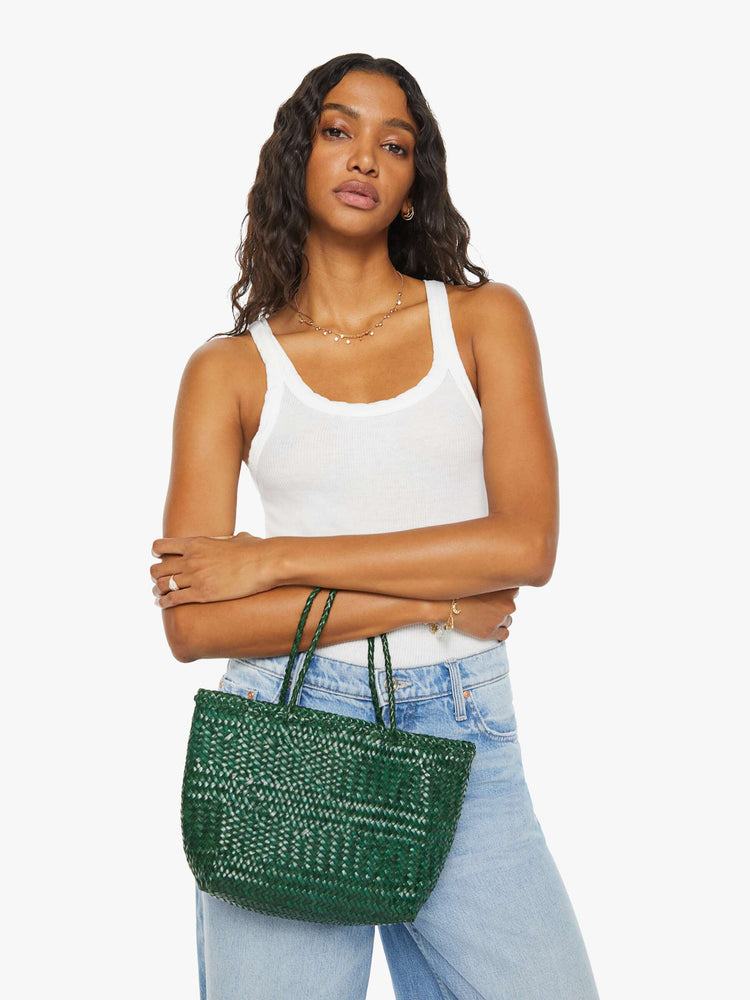 Front view of a woman holding a small green woven purse.