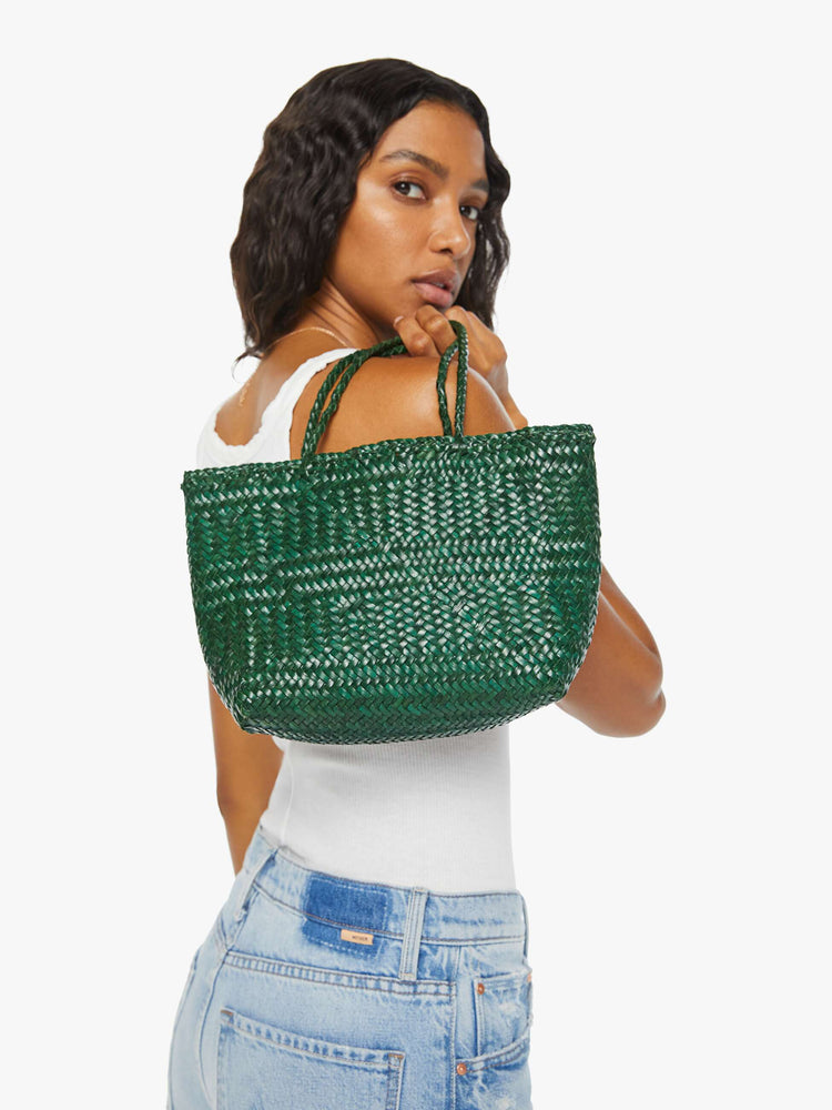 Back view of a woman holding a small green woven purse.