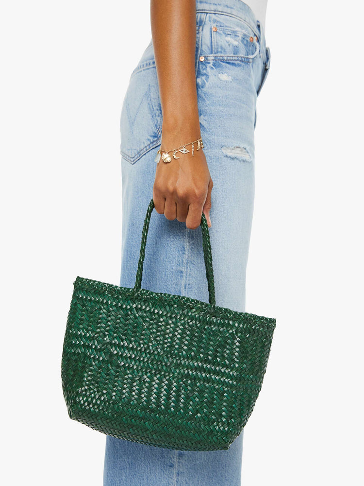 Side view of a woman holding a small green woven purse.