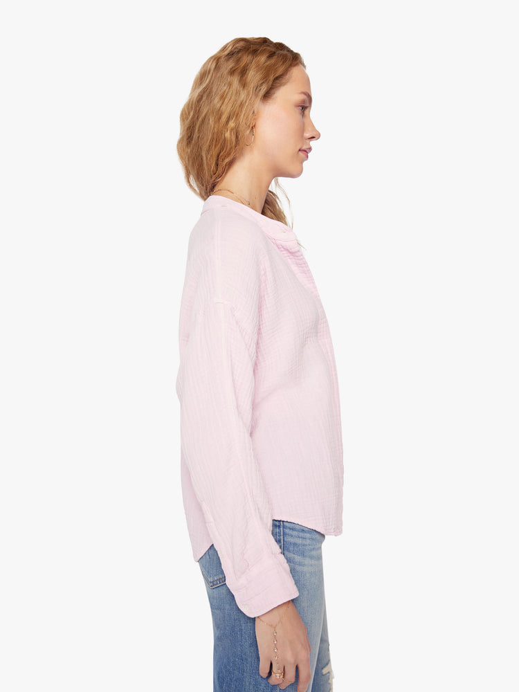 Side view of a woman baby pink blouse with a V-neck with buttons down the front, a curved hem and an airy fit.