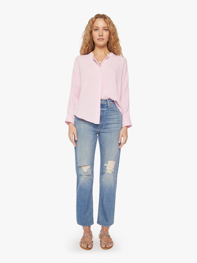 Full body view of a woman baby pink blouse with a V-neck with buttons down the front, a curved hem and an airy fit.
