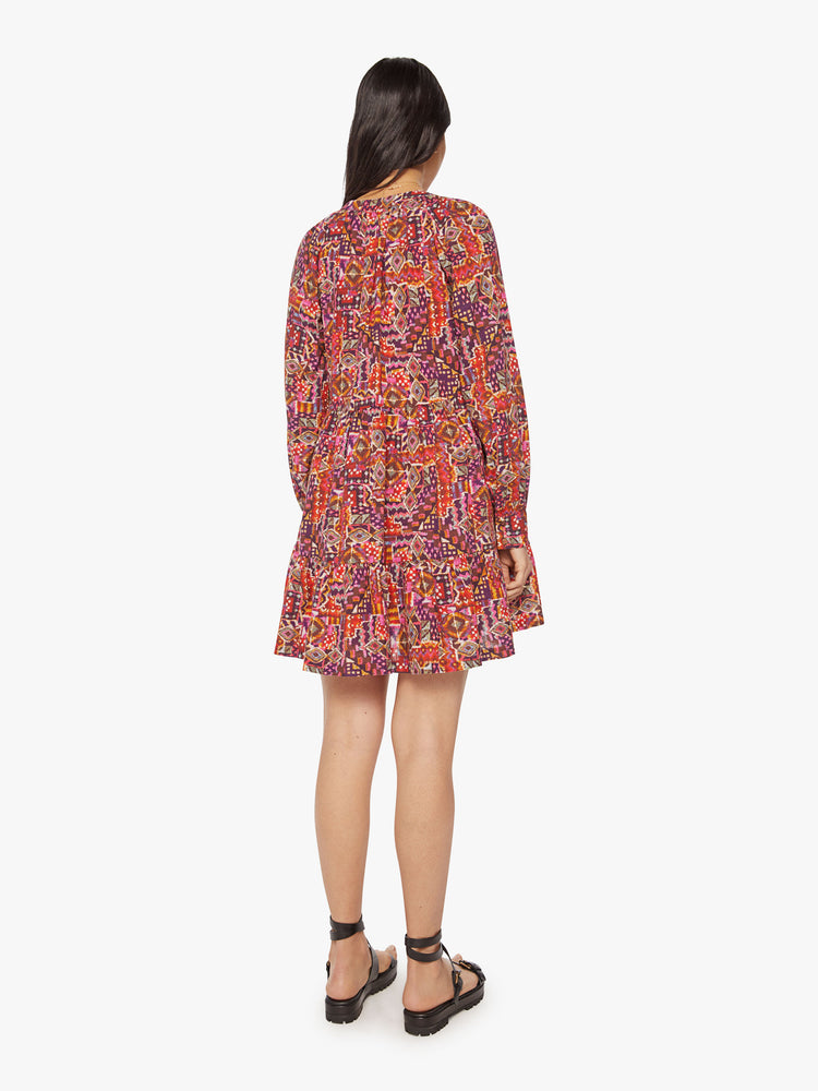 Back view of a woman colorful kaleidoscope print with a buttoned vneck, long sleeves and ruffled skirt.