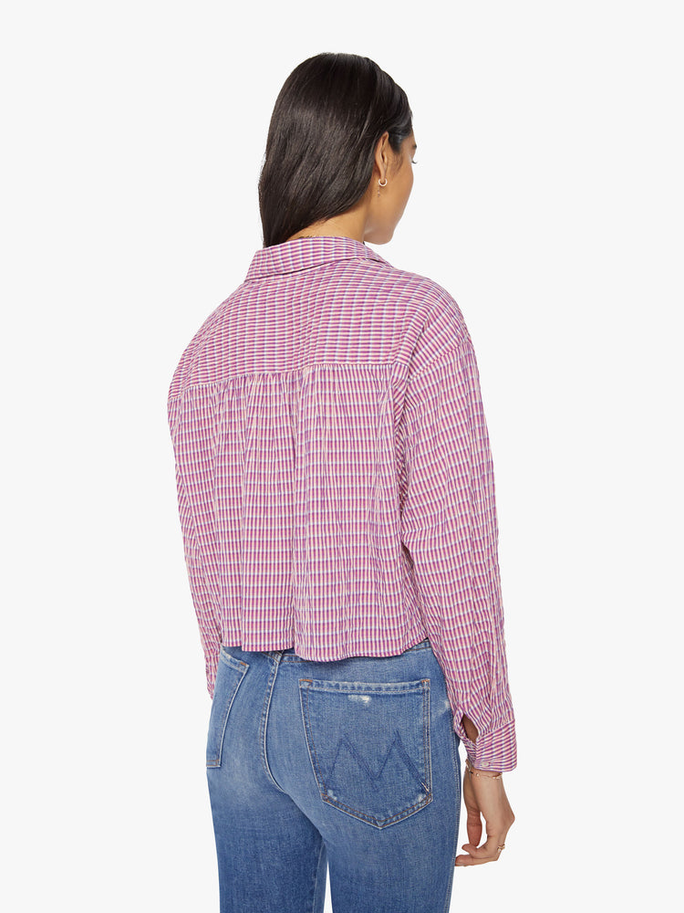 Back view of a woman coral-pink shirt with cropped hem, vneck with buttons down the front.