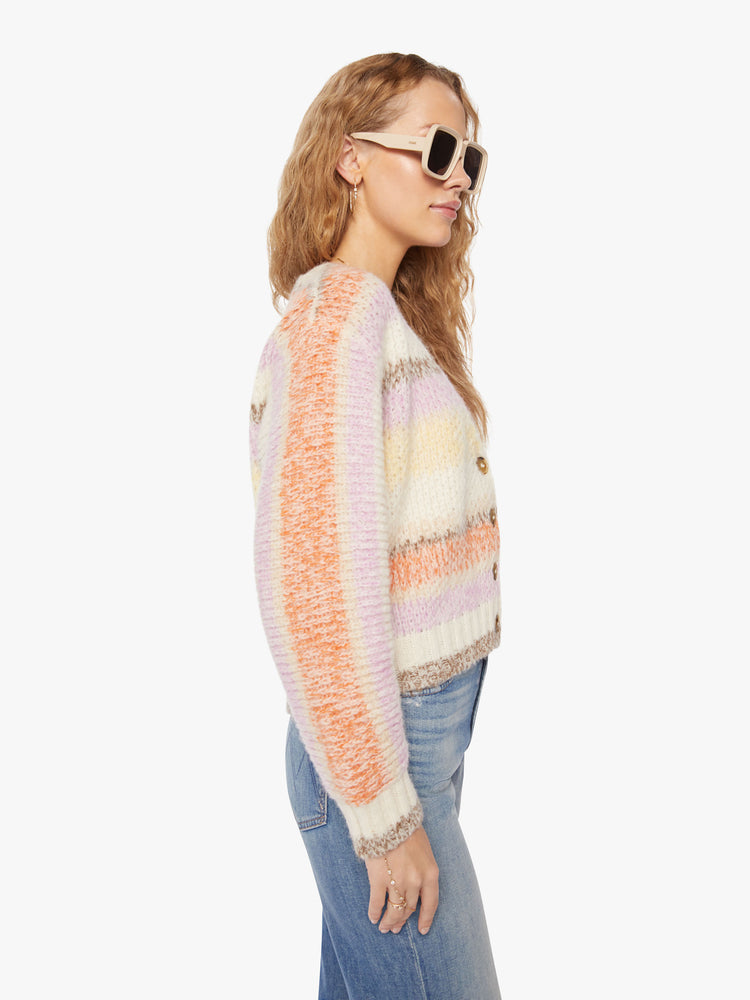 Side view of a woman vneck, long sleeve, cropped hem, buttons down the front cardigan in a pastel horizontal stripe pattern.