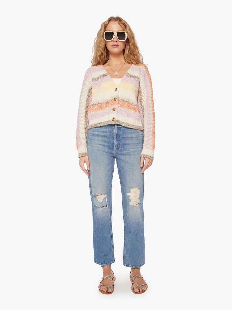 Full body view of a woman vneck, long sleeve, cropped hem, buttons down the front cardigan in a pastel horizontal stripe pattern.