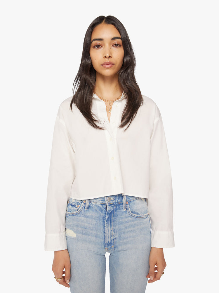 Front view of a woman white cropped button-up designed with drop shoulders, a cropped hem and boxy fit.