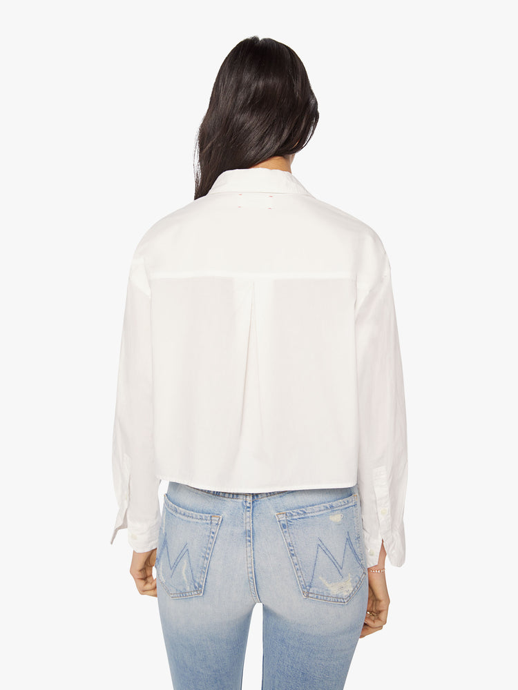 Back  view of a woman white cropped button-up designed with drop shoulders, a cropped hem and boxy fit.