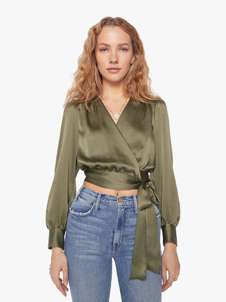 Front view of a womans shirt with a V-neck, long sleeves and a cropped hem that ties in an olive-green hue.