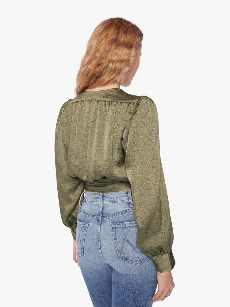 Back view of a womans shirt with a V-neck, long sleeves and a cropped hem that ties in an olive-green hue.