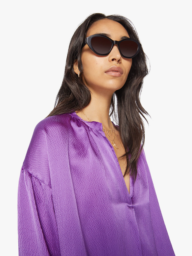 Close up view of a woman longsleeve blouse in a silk purple topaz hue designed with a V-neck, drop shoulders and a flowy fit.