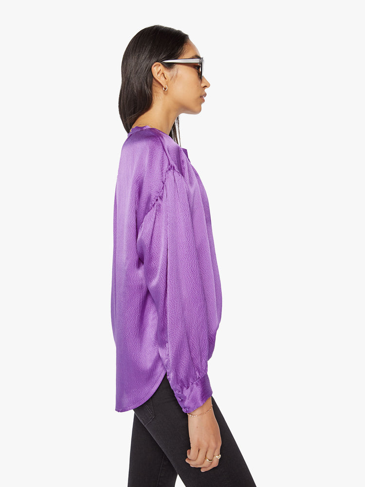 Side view of a woman longsleeve blouse in a silk purple topaz hue designed with a V-neck, drop shoulders and a flowy fit.