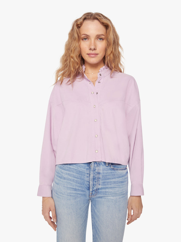 Front view of a woman soft lilac shirt with a ruffled V-neck that buttons, drop shoulders, long sleeves, a cropped hem and a boxy fit.