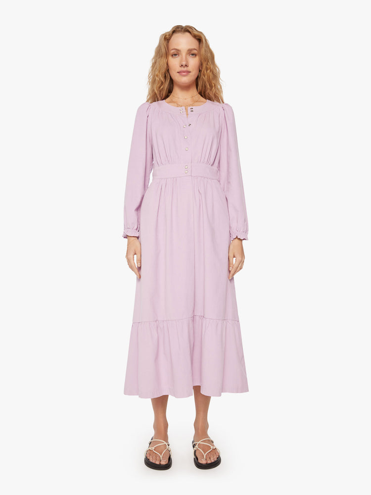 Front view of woman soft lilac dress with a buttoned V-neck, long sleeves, a gathered waistline and a tiered skirt.