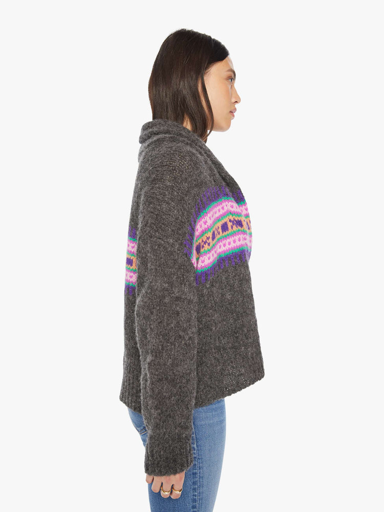 Side view of a woman cardigan with a shawl collar, drop shoulders and buttons down the front with a colorful knit pattern across the chest.