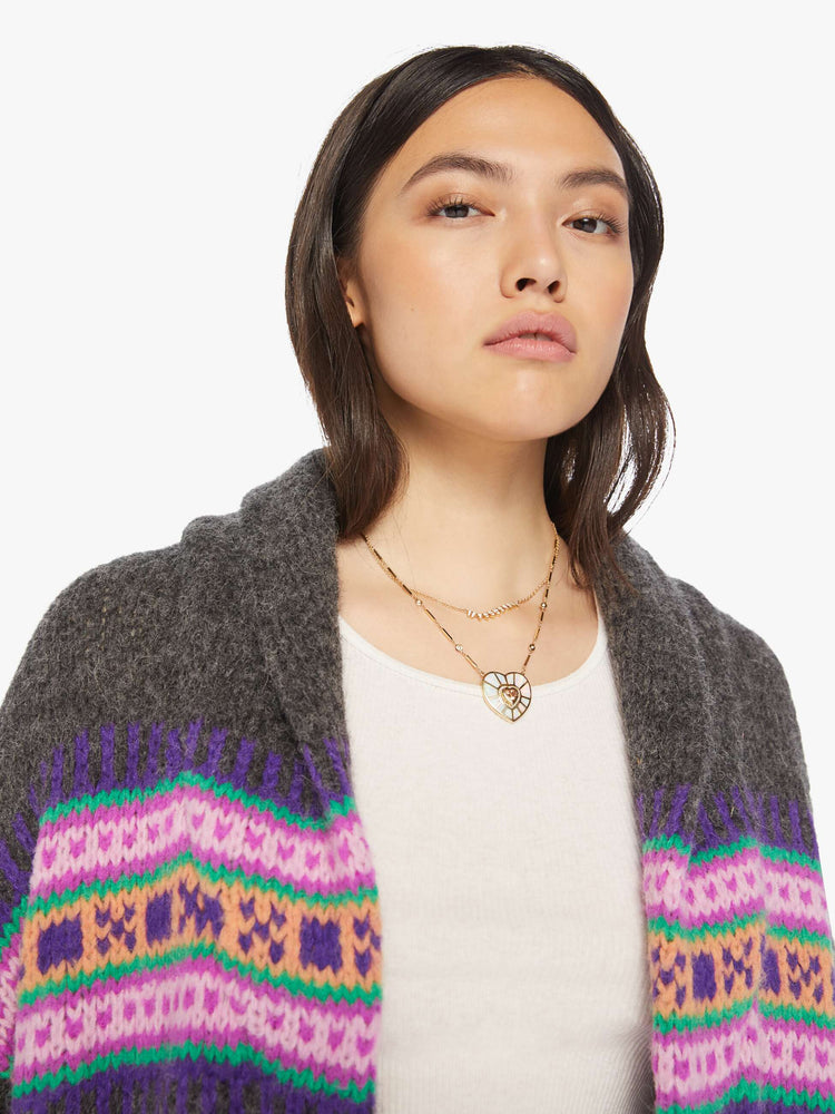 Close up view of a woman cardigan with a shawl collar, drop shoulders and buttons down the front with a colorful knit pattern across the chest.