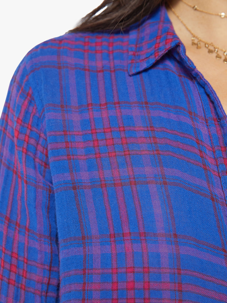 Close up view of a women blue plaid button-down long-sleeve shirt features a V-neck and curved hem with a light and airy fit.