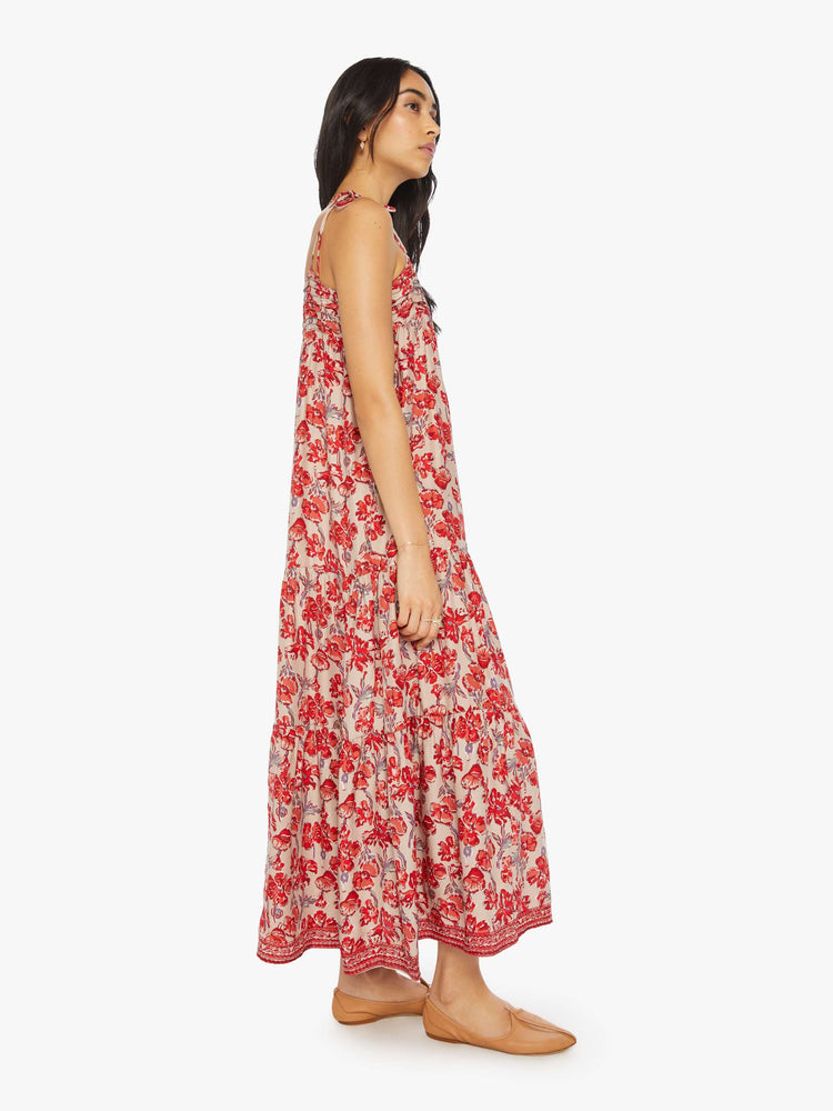 Side view of a woman dress features slim adjustable ties at the shoulders and a floaty, tiered skirt that emphasizes the relaxed fit in a nude and red floral print.