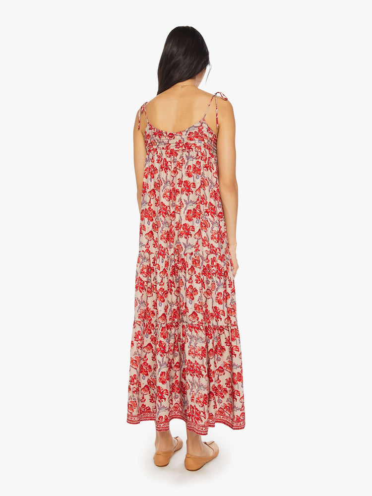 Back view of a woman dress features slim adjustable ties at the shoulders and a floaty, tiered skirt that emphasizes the relaxed fit in a nude and red floral print.
