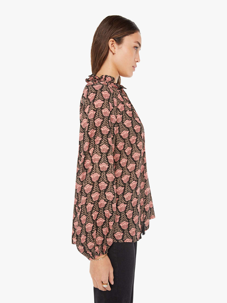 Side view of a womens blouse with a black and pink floral print and balloon sleeves.
