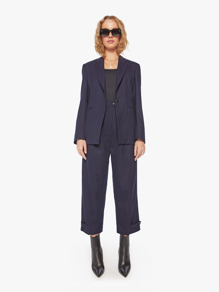 Full body view of a woman wool navy blazer with a V-neck, padded shoulders, a button closure and a slightly narrow fit.