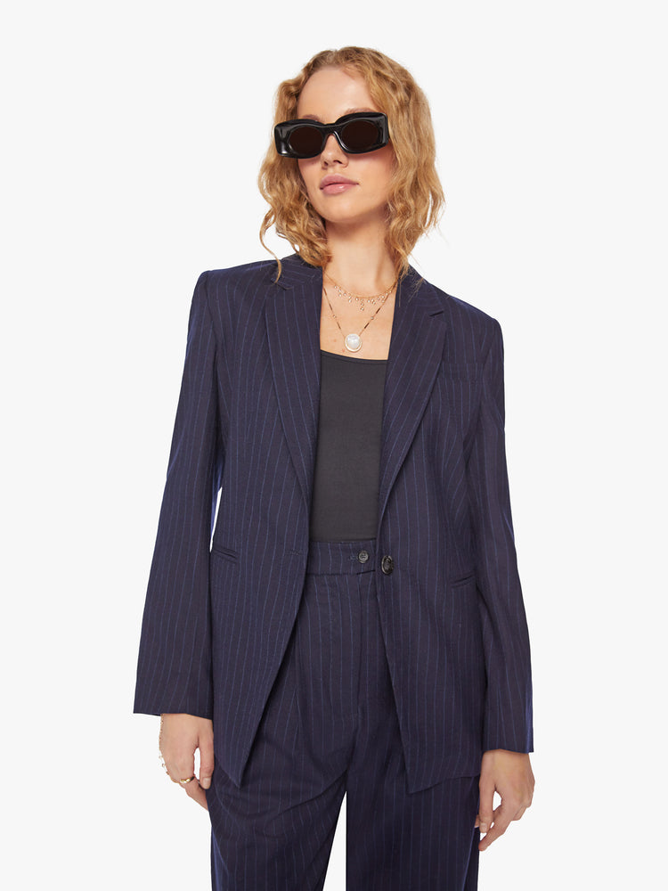 Front view of a woman wool navy blazer with a V-neck, padded shoulders, a button closure and a slightly narrow fit.