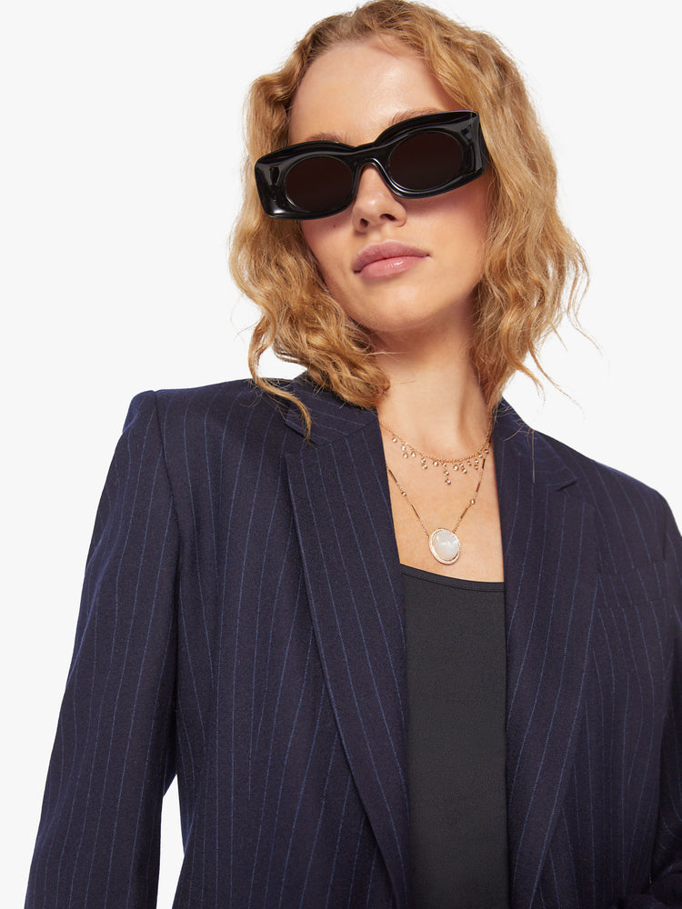 Close up view of a woman wool navy blazer with a V-neck, padded shoulders, a button closure and a slightly narrow fit.