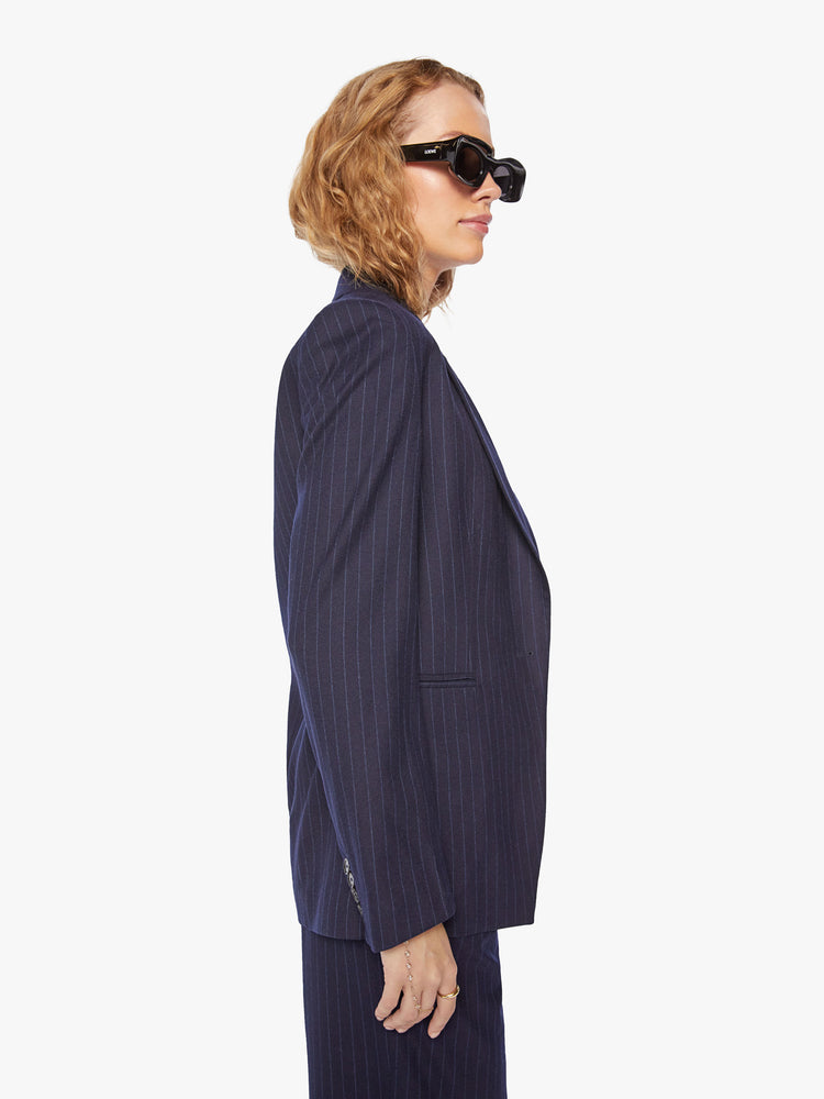 Side view of a woman wool navy blazer with a V-neck, padded shoulders, a button closure and a slightly narrow fit.