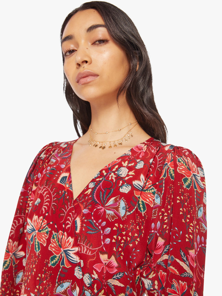 Close up view of a woman red silk wrap midi dress with a V-neck, cropped long sleeves, and a wrapped design that ties at the waist.