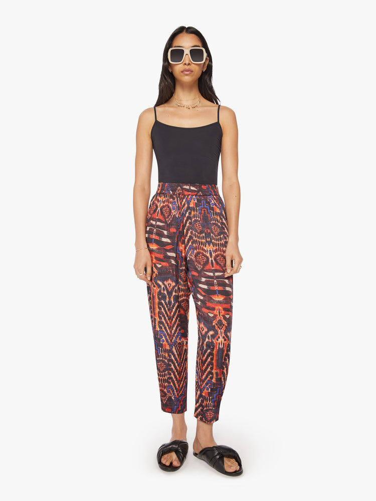 Front view of a woman trousers feature a high rise, loose tapered leg and an ankle-length hem in a kaleidoscope-inspired print.