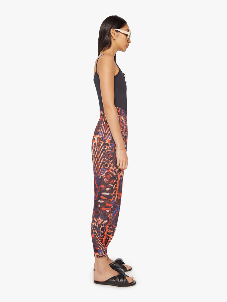 Side view of a woman trousers feature a high rise, loose tapered leg and an ankle-length hem in a kaleidoscope-inspired print.